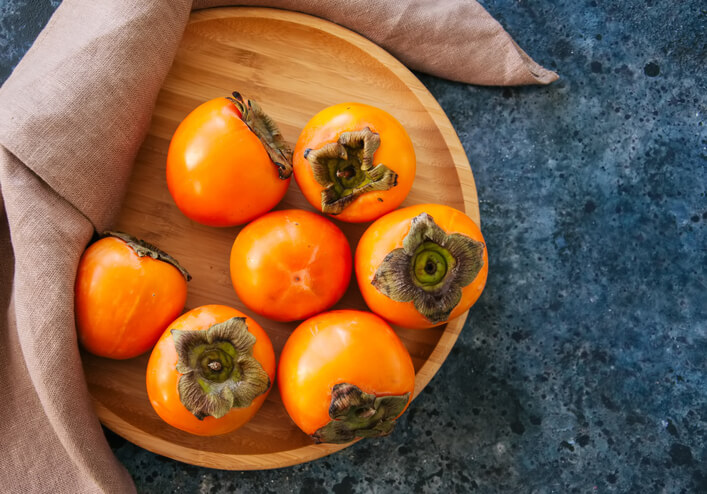Wooden plate of persimmons