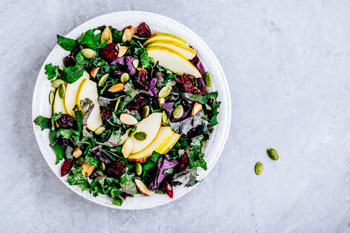 image of kale salad with apples, cranberries and pumpkin seeds