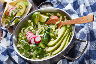 Bowl of chile verde with radish, avocado, cilantro