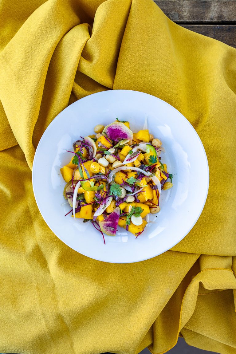 Mango Salad with watermelon, daikon and cilantro in a bowl on a yellow tablecloth