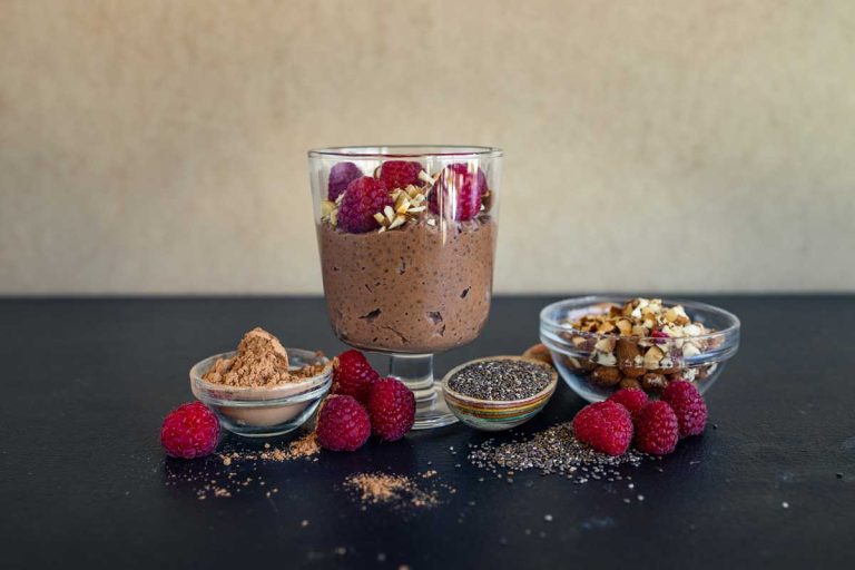chocolate chia pudding in a glass with raspberries and chia seeds