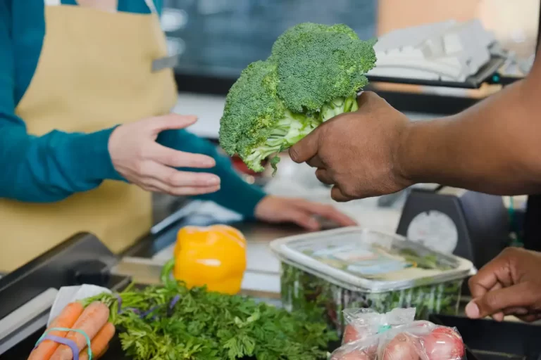 customer handing a sales person broccoli