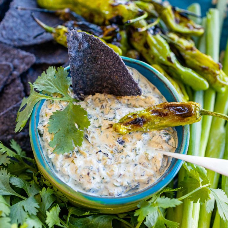 Blistered Shisito Crema in a bowl surrounded by shisito peppers and chips