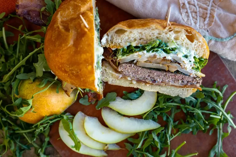 A burger from the Co-op deli cut in half with sliced apple and arugula
