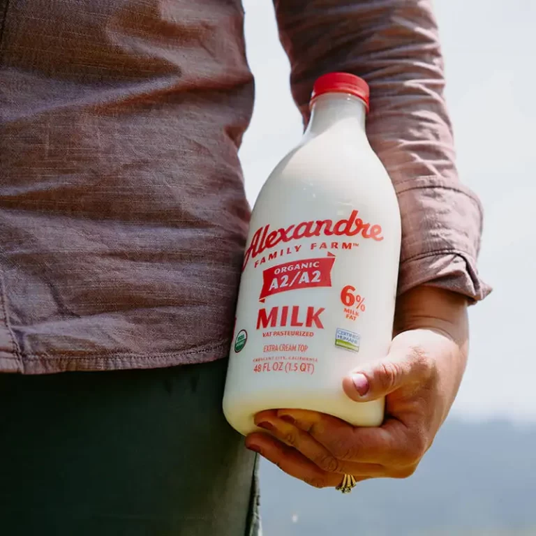 A close up of a person holding a bottle of Alexandre Farms milk.