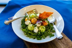 A melon and arugula salad with crispy prosciutto.