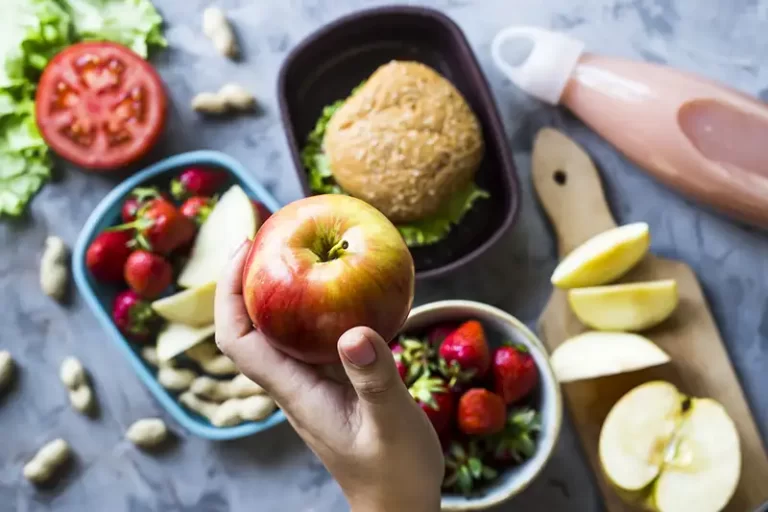 A lunch box with a person holding an apple.