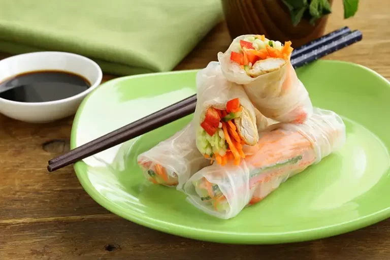 Chicken spring rolls on a green plate with chopsticks.