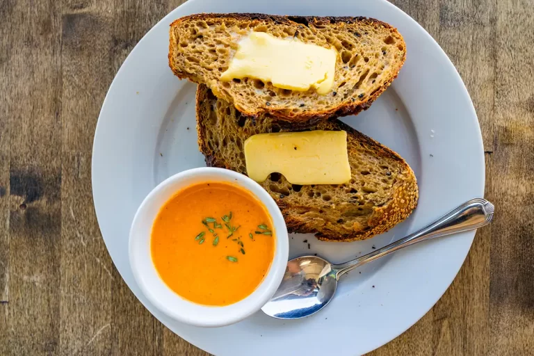 A bowl of heirloom tomato soup with fresh bread and butter.