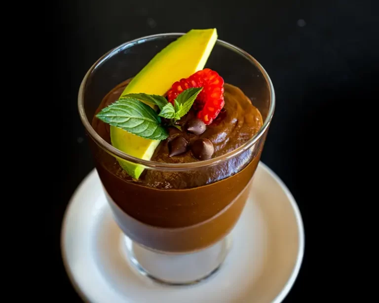 Avocado Mousse in a glass topped with a slice of avocado and strawberry.