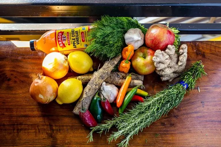 Assorted ingredients for Fire Cider on a wooden table.