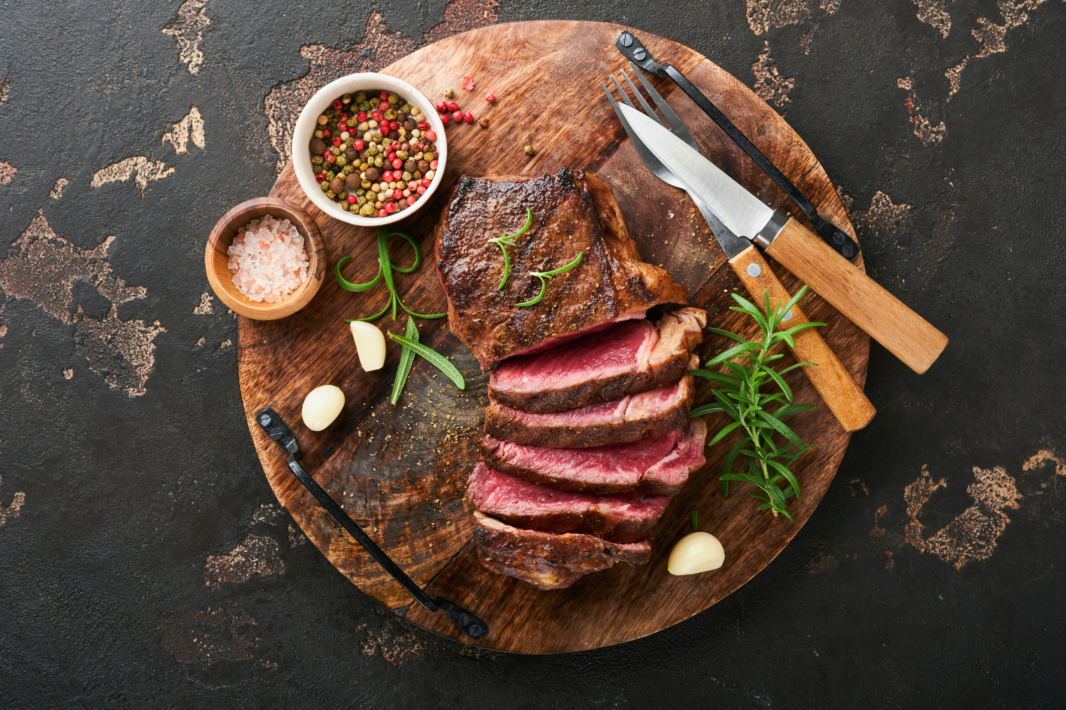 A grilled steak sliced into pieces on a cutting board.