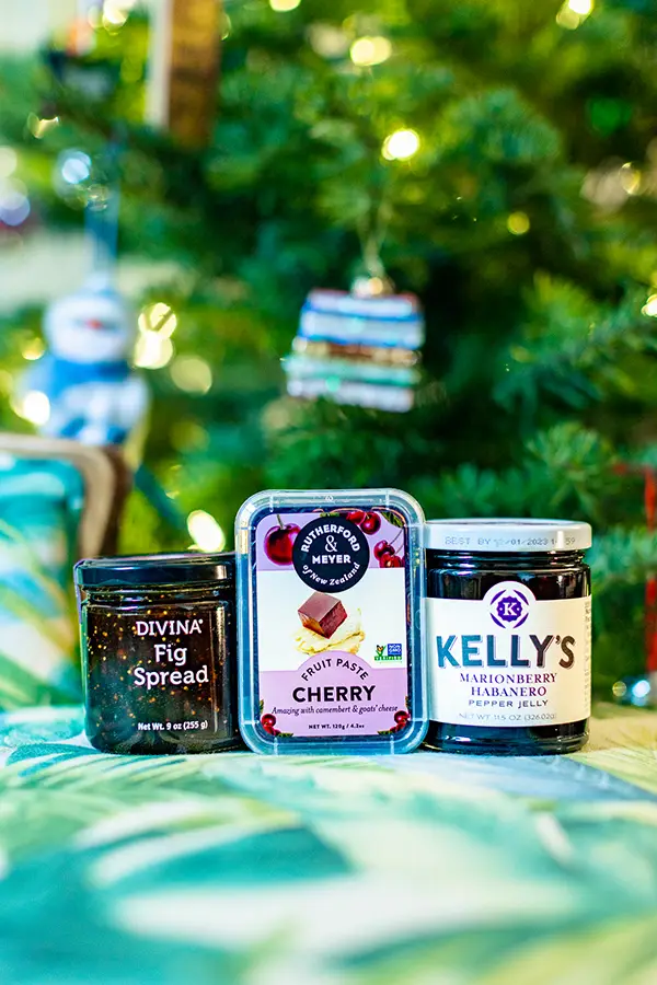 A collection of specialty jam and jelly in front of a christmas tree.