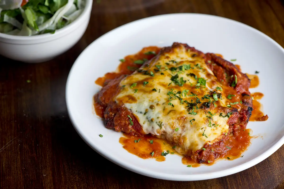 Chicken parmigiana Traditional Italian comfort dish. Chicken breast covered in breadcrumbs lightly fried, topped with homemade marinara, melted mozzarella, parmigiana provolone and Italian parsley.