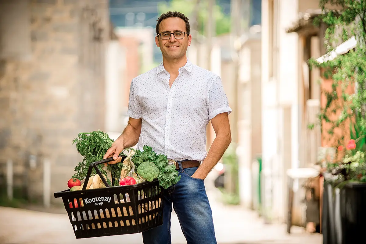 A portrait of Jon Steinman, holding a basket of produce.