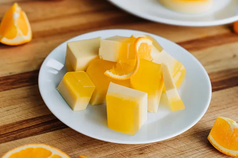 Orange creamsicle juice jello cut into squares on a plate.
