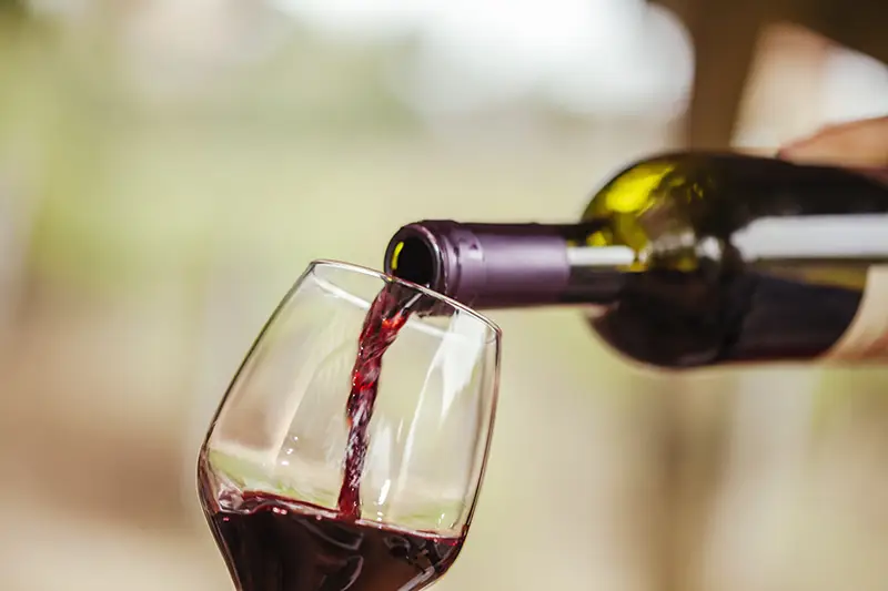 Red wine being poured from a bottle into a glass.