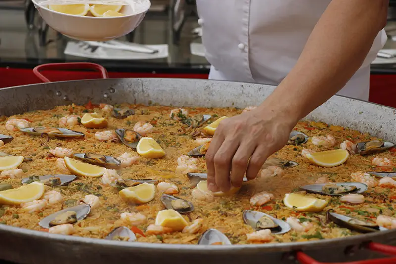 A close up view of someone cooking a large pan of paella.