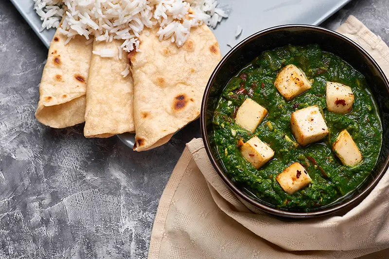 Palak Paneer with chapati and basmati rice at grey concrete background.