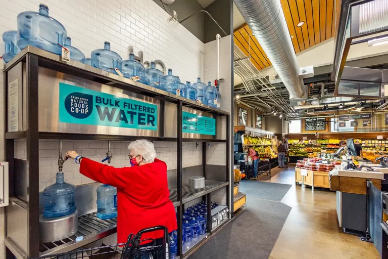 A person filling a container with water from the bulk water station at the Co-op.