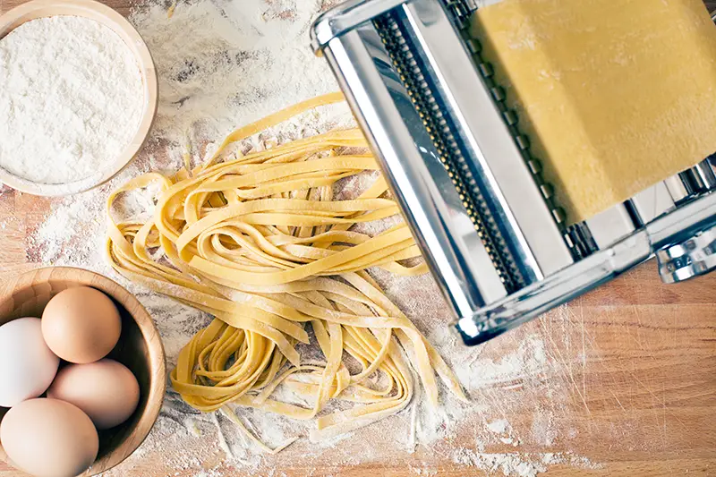 Handmade pasta being made with a pasta machine.