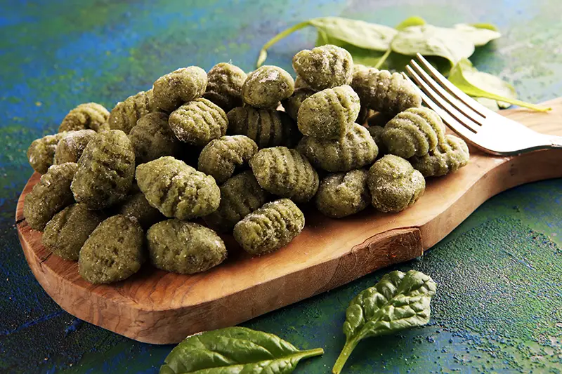 Fresh handmade spinach gnocchi on a cutting board.