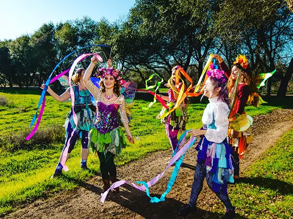 A group photo of pixies from Pixie Tribe with colorful outfits and ribbons.