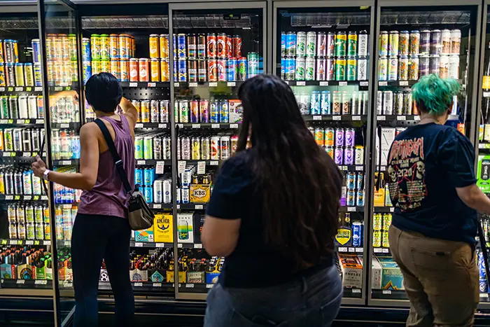 A wide view of the beer coolers filled with bottles and cans as customers shop.