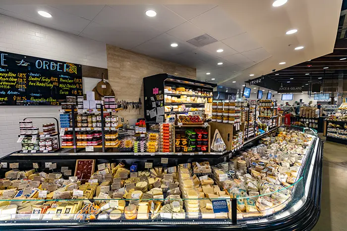 A wide view of the cheese counter and cheese case filled with hundreds of different types of cheese.
