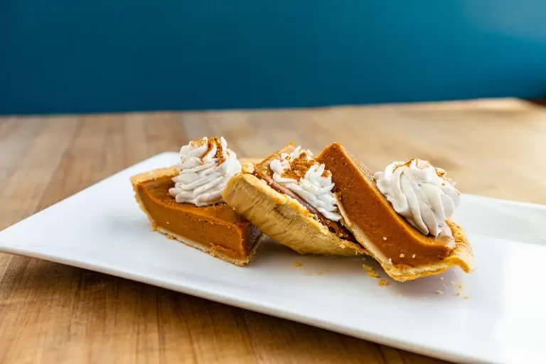 Three pieces of pumpkin pie topped with whipped cream.