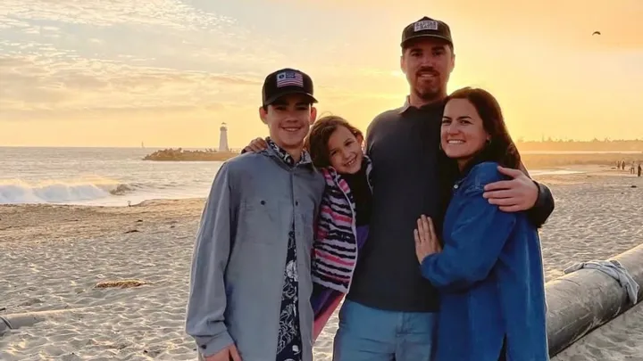 A photo of Brian Munn and his family on the beach at sunset.