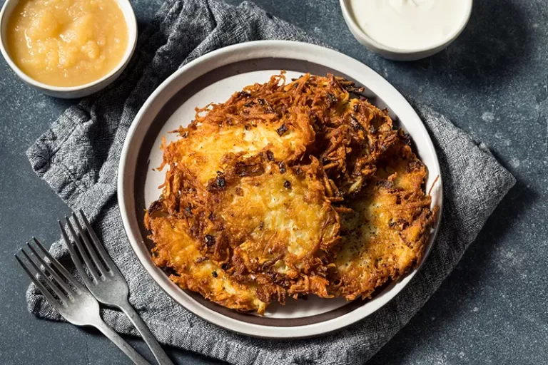 Homemade crispy potato latkes with a side of applesauce and sour cream.