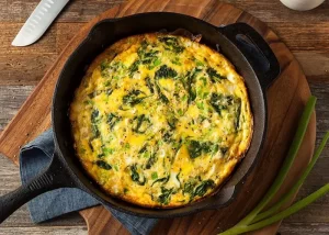 A frittata with spinach in a cast iron pan.